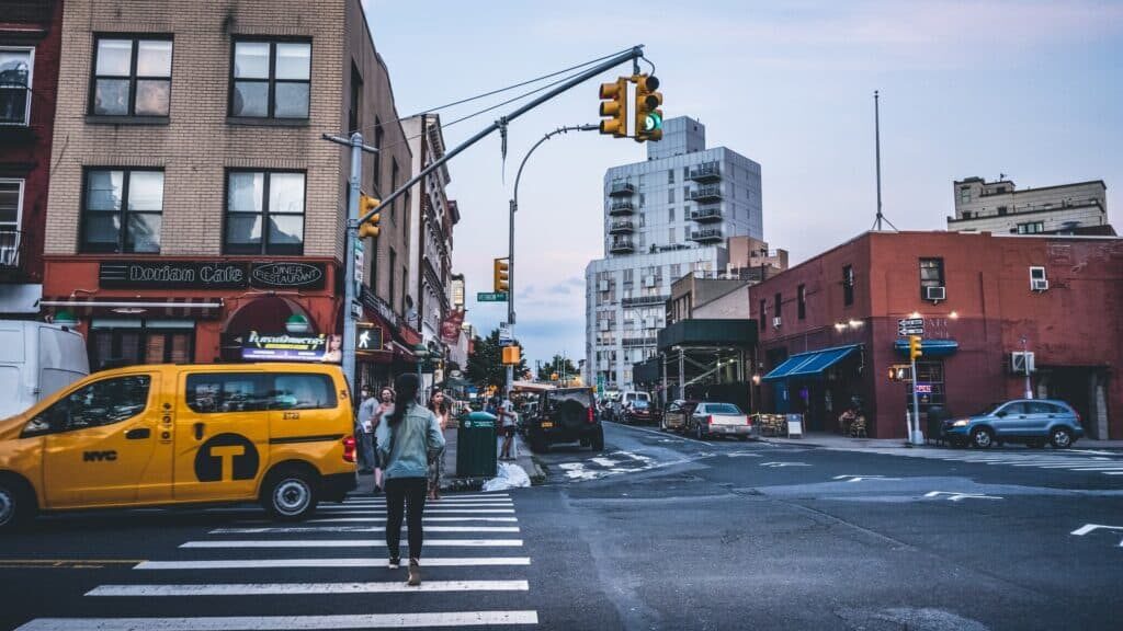 a person crossing a street with a yellow van and buildings