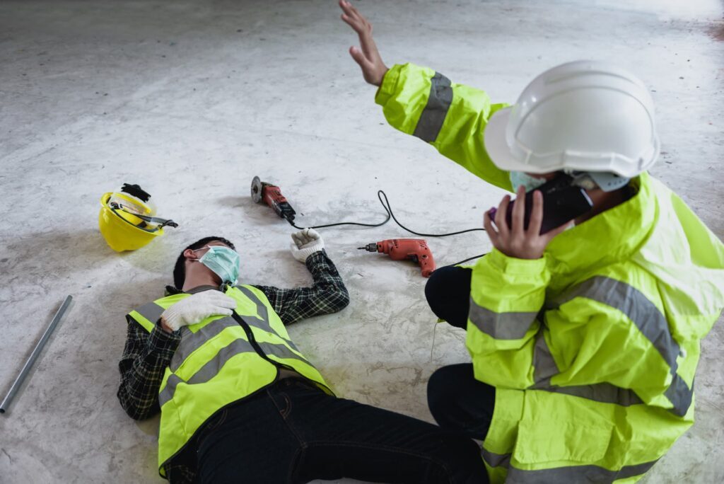 a person in safety vest and helmet with a drill on the ground