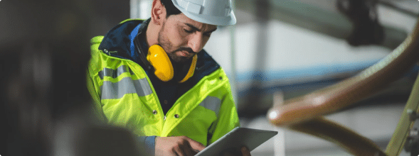 a person wearing a hard hat and yellow jacket doing safety checks